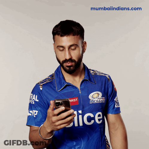 A Man In A Blue Mumbai Indians Jersey Looks At His Cell Phone GIF
