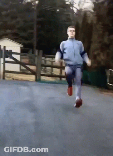A Man In A Blue Nike Jacket Is Running On A Road GIF