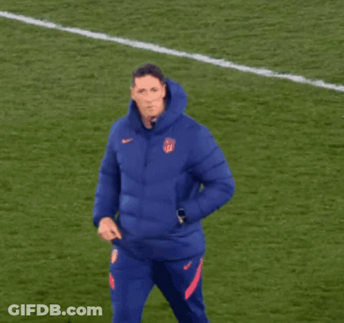 A Man In A Blue Nike Jacket Stands On A Field GIF