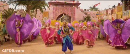 A Man In A Blue Outfit Is Dancing In Front Of A Crowd Of People GIF