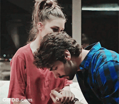 A Man In A Blue Plaid Shirt Kisses A Woman On The Cheek GIF