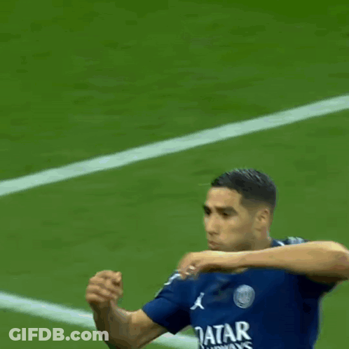 A Man In A Blue Qatar Airways Shirt Stands On A Field GIF