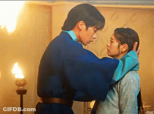 A Man In A Blue Robe Is Touching A Woman 'S Forehead . GIF