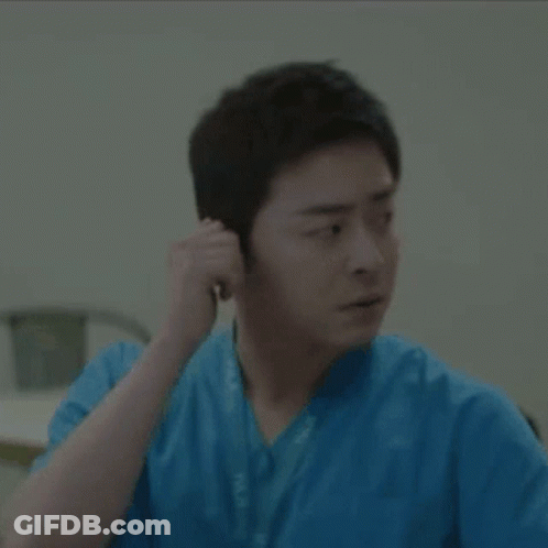 A Man In A Blue Scrub Is Adjusting His Ear Buds GIF