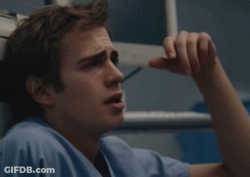 A Man In A Blue Scrub Top Is Holding His Head GIF