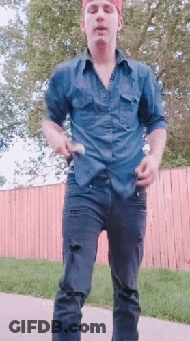 A Man In A Blue Shirt And Black Jeans Is Dancing GIF