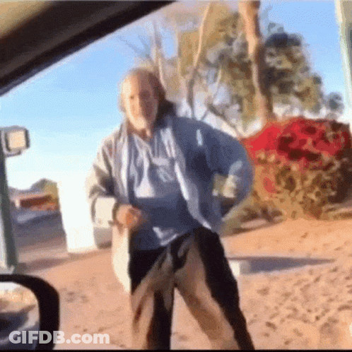 A Man In A Blue Shirt And Black Pants Is Dancing In A Car . GIF