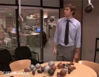 A Man In A Blue Shirt And Black Tie Is Standing In Front Of A Table With Boxing Gloves On It GIF