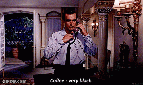 A Man In A Blue Shirt And Black Tie Is Talking On A Phone And Says Coffee - Very Black GIF