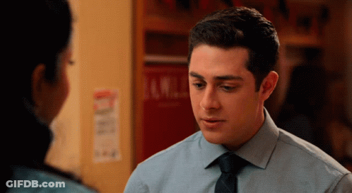 A Man In A Blue Shirt And Black Tie Looks At A Woman GIF