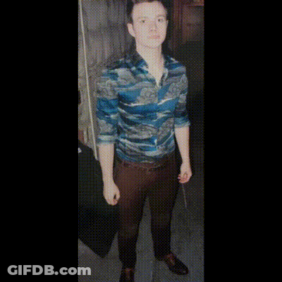 A Man In A Blue Shirt And Blue Shoes Is Standing In A Room GIF