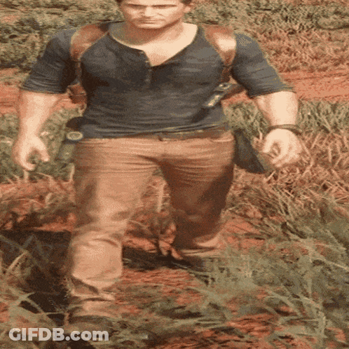 A Man In A Blue Shirt And Brown Pants Is Walking In The Grass GIF