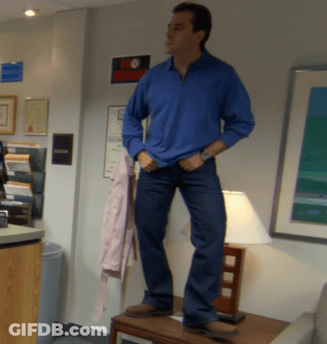 A Man In A Blue Shirt And Jeans Stands On A Table GIF