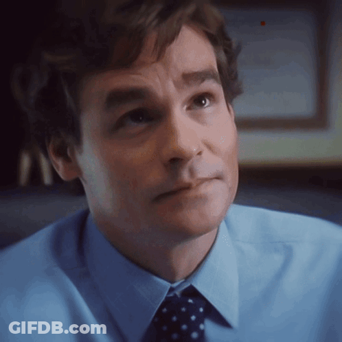 A Man In A Blue Shirt And Polka Dot Tie Looks To The Side GIF