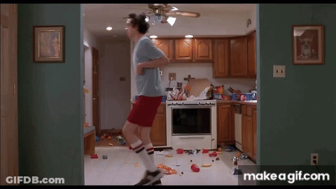 A Man In A Blue Shirt And Red Shorts Is Jumping In A Kitchen . GIF
