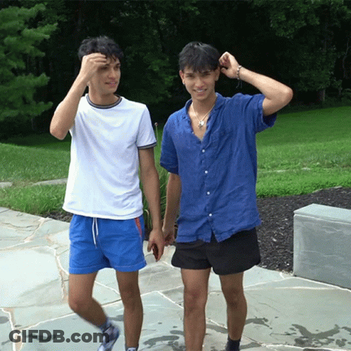 A Man In A Blue Shirt And Shorts Is Walking With Another Man In A White Shirt GIF