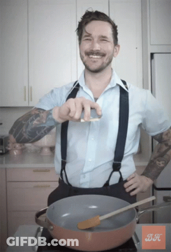 A Man In A Blue Shirt And Suspenders Is Standing In Front Of A Pot With A Spatula In It GIF