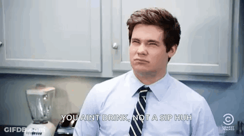 A Man In A Blue Shirt And Tie Is Making A Face In A Kitchen . GIF