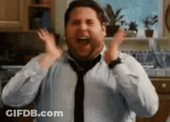 A Man In A Blue Shirt And Tie Is Screaming With His Hands In The Air . GIF