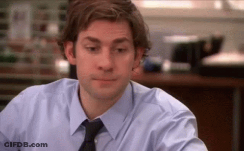 A Man In A Blue Shirt And Tie Is Sitting At A Table In An Office . GIF