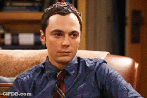 A Man In A Blue Shirt And Tie Is Sitting In A Chair And Making A Funny Face . GIF