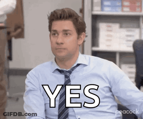 A Man In A Blue Shirt And Tie Is Sitting In An Office And Says Yes GIF