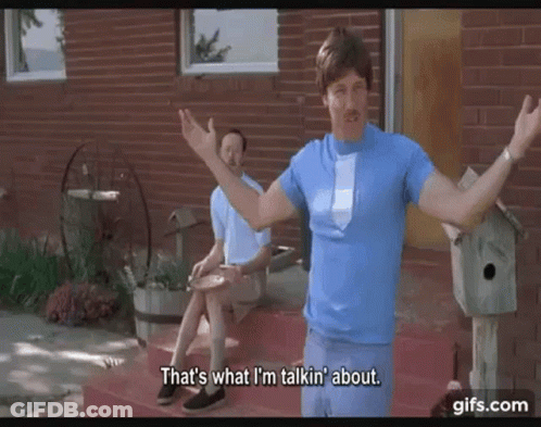 A Man In A Blue Shirt And Tie Is Standing In Front Of A Brick House Talking To Another Man . GIF