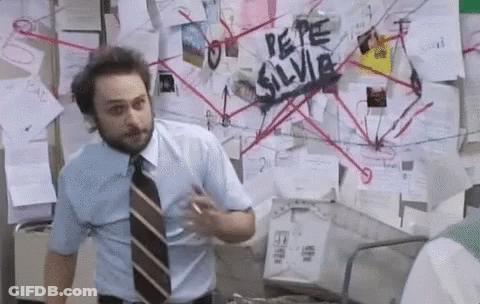 A Man In A Blue Shirt And Tie Is Standing In Front Of A Bulletin Board With Papers On It . GIF