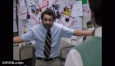 A Man In A Blue Shirt And Tie Is Standing In Front Of A Bulletin Board With Papers On It . GIF