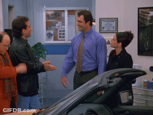 A Man In A Blue Shirt And Tie Is Standing Next To A Woman In A Black Coat GIF