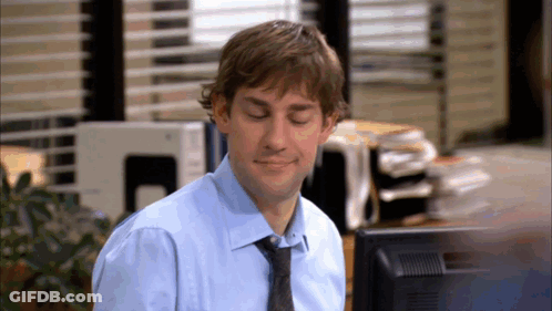 A Man In A Blue Shirt And Tie Sitting In Front Of A Computer Monitor GIF