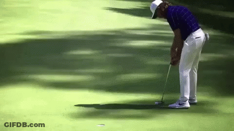 A Man In A Blue Shirt And White Pants Is Putting A Golf Ball GIF