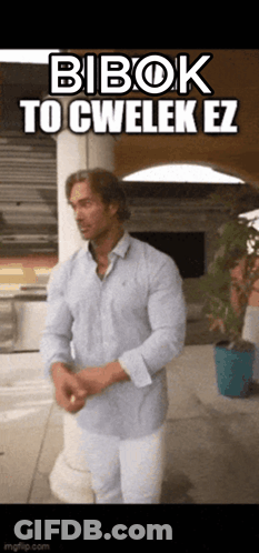 A Man In A Blue Shirt And White Pants Is Standing In Front Of A Sign That Says Bibok To Cwelek Ez . GIF
