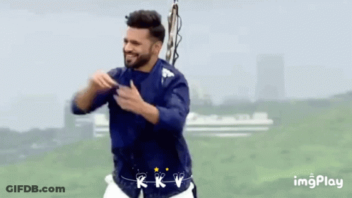 A Man In A Blue Shirt And White Shorts Is Dancing In A Field GIF