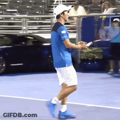 A Man In A Blue Shirt And White Shorts Is Holding A Tennis Racket GIF