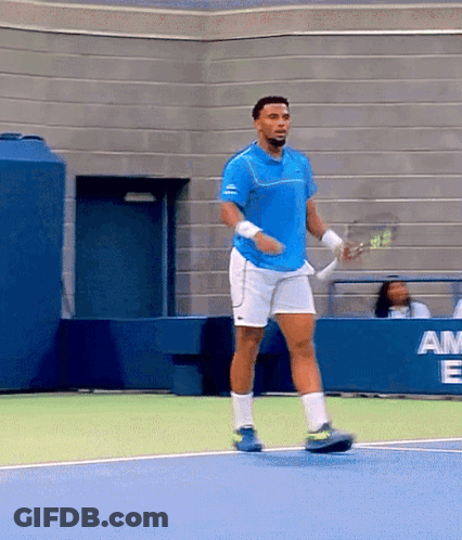 A Man In A Blue Shirt And White Shorts Is Holding A Tennis Racquet GIF