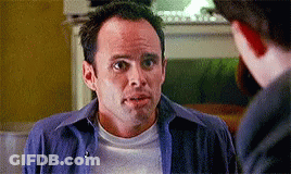 A Man In A Blue Shirt And White T-Shirt Is Talking To Another Man GIF