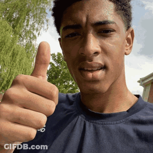 A Man In A Blue Shirt Gives A Thumbs Up Sign GIF