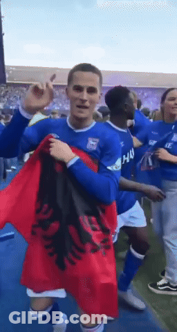 A Man In A Blue Shirt Holds A Red Flag GIF