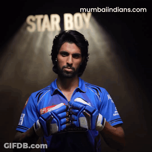 A Man In A Blue Shirt Holds His Gloves In Front Of A Star Boy Sign GIF