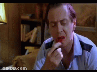 A Man In A Blue Shirt Is Applying Red Lipstick On His Lips GIF