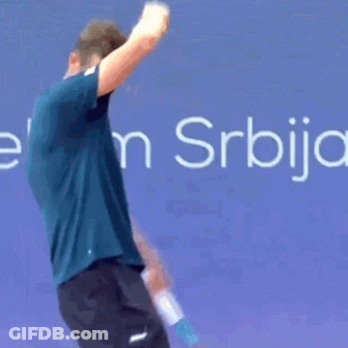 A Man In A Blue Shirt Is Bending Over In Front Of A Sign That Says Elek S. GIF