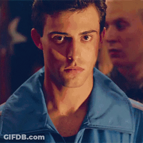 A Man In A Blue Shirt Is Covering His Face With His Hand GIF