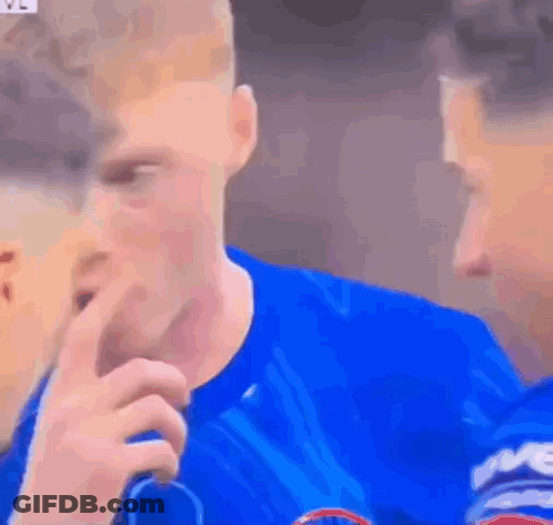 A Man In A Blue Shirt Is Covering His Mouth With His Hand While Another Man Looks On . GIF