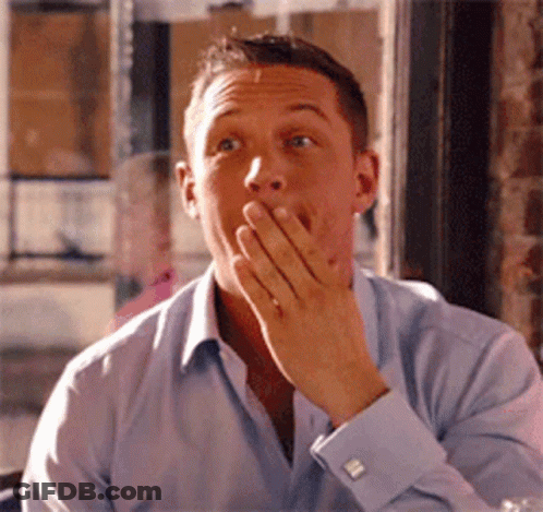 A Man In A Blue Shirt Is Covering His Mouth With His Hands GIF