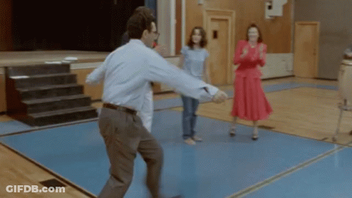 A Man In A Blue Shirt Is Dancing In A Gym With Two Women GIF