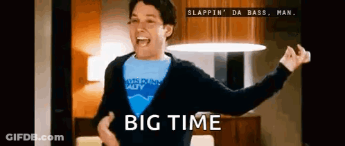 A Man In A Blue Shirt Is Dancing In A Living Room With The Words Big Time Written On The Bottom . GIF