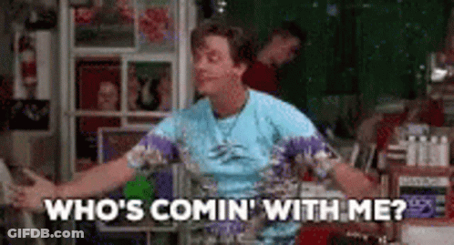 A Man In A Blue Shirt Is Dancing In A Room And Saying `` Who 'S Comin ' With Me ? '' . GIF