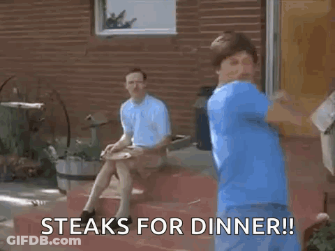 A Man In A Blue Shirt Is Dancing In Front Of A Brick Building While Another Man Sits On The Steps . GIF