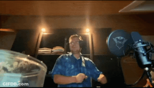 A Man In A Blue Shirt Is Dancing In Front Of A Microphone That Says Trust GIF